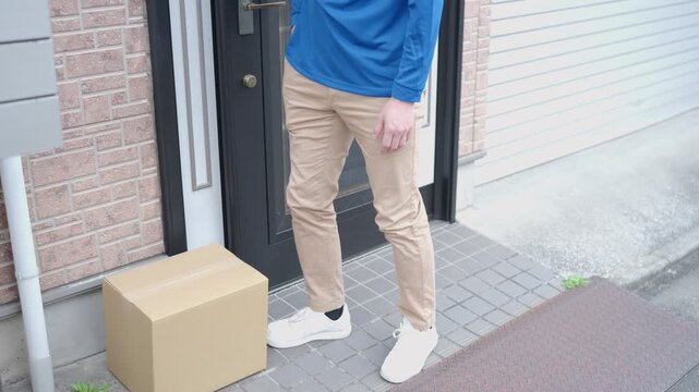 玄関前に置き配する配達員