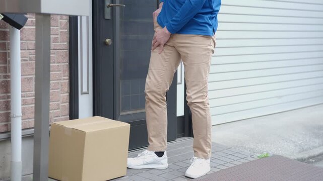 玄関前に置き配する配達員