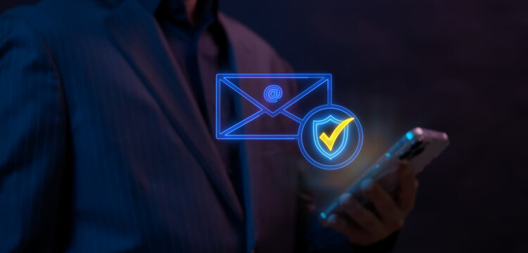 Businessman holding smartphone while supporting glowing email envelope icon with security shield checkmark badge. Encrypted email message protection and secure business communication concept.