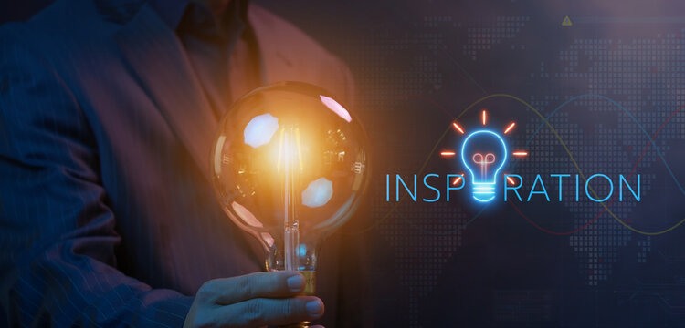 Businessman holding bright glowing lightbulb with INSPIRATION text and lightbulb icon beside display. Creative idea generation, business inspiration discovery, and strategic thinking concept.
