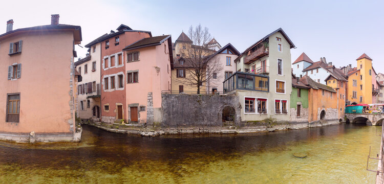 Traditional colorful houses, stone bridge and waterfront promenade along a canal in Annecy, France.
