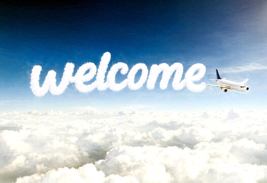Beautiful aerial view of an airplane flying above clouds with welcome text written in skywriting style