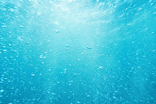 Underwater turquoise ocean background with air bubbles, bright sunlight rays through clear blue sea water, aquatic nature texture