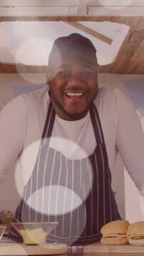 Animation of spots of light floating over smiling african american fast food seller