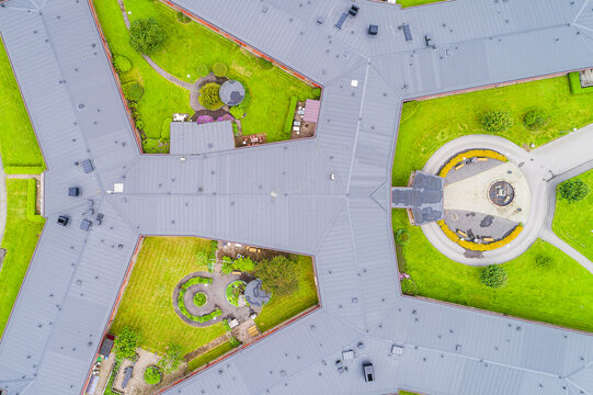 Aerial view of a modern building complex with grey roofs, green lawns, and a circular driveway in Molndal, Vastra Gotaland County, Sweden.