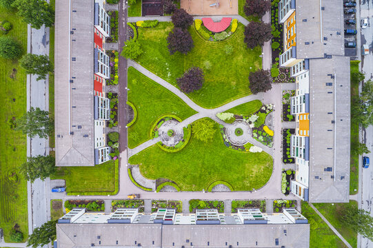 Aerial view of residential apartment buildings surrounding a lush green courtyard with walking paths and trees in a suburban neighborhood Molndal, Vastra Gotaland County, Sweden.