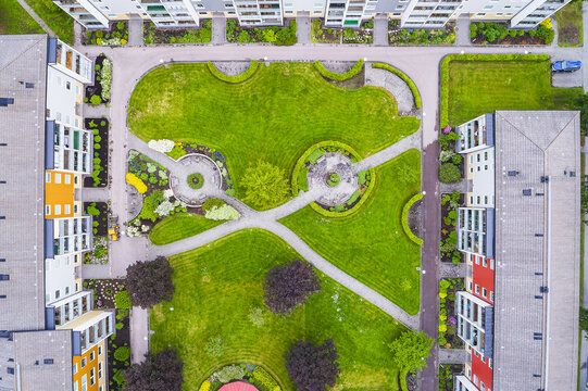 Aerial view of a residential courtyard with lush green lawns, manicured hedges, paved pathways, and modern apartment buildings in Molndal, Vastra Gotaland County, Sweden.