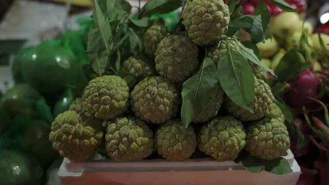 Fresh Fruit Display. Vietnamese Market Soursop Closeup. Close View Of Fresh Soursop In Market Environment. Humid Evening Street Market Showcasing Vibrant Green Soursop Fruits