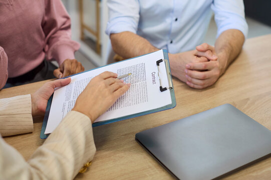 Couple and advisor review contract during consultation. They confirm signature on finance loan document and discuss mortgage. Concept conveys trustworthy financial agreement and approval.