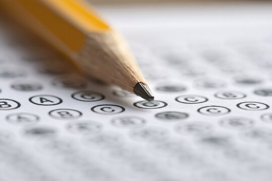 Close-up of a sharpened pencil poised over a multiple-choice test paper with circled answers