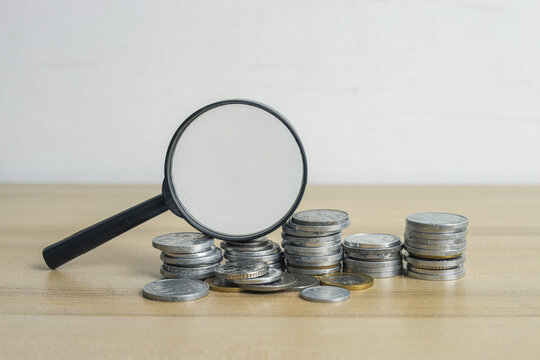 Closeup of Magnifying Glass Placed on Stacks of Coins