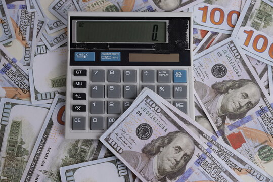 Top View of Electronic Calculator Placed on Scattered One Hundred Dollar Bills