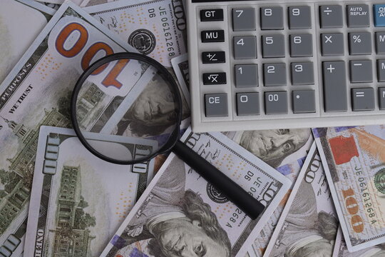 Top View of Calculator with Magnifying Glass on Scattered Dollar Banknotes
