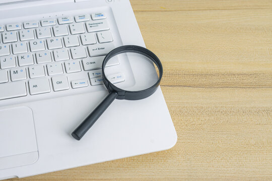 Closeup of Magnifying Glass Resting on Laptop Keyboard