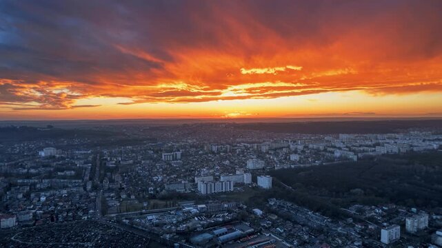 Stunning sunset over cityscape with vibrant orange and blue sky, beautiful urban twilight aerial motion lapse.
