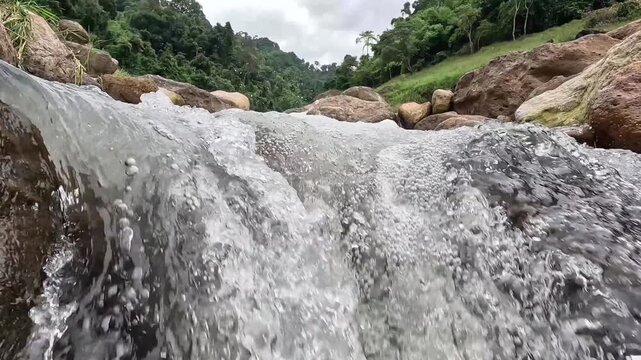 Fresh natural mountain stream flowing over rocks in a lush green forest. Scenic water stream footage in tropical nature.