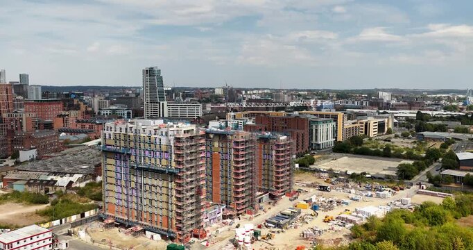 Aerial footage of Leeds city centre showing a large construction site with new high rise buildings scaffolding cranes modern developments residential towers and dense urban architecture in Yorkshire