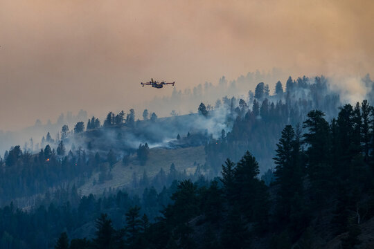 Firefighting plane flying over a smoky mountain forest