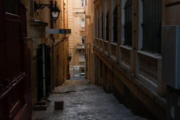 Fototapeta premium Narrow street with parked cars leading to the sea in valletta, malta