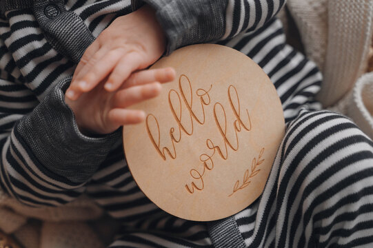 Newborn baby rests with a hello world sign