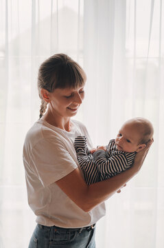 Smiling mother lovingly holds her newborn baby boy