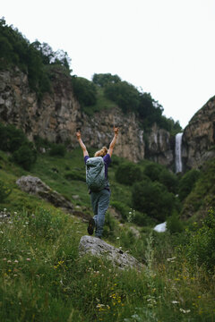 Woman celebrates hiking success near a waterfall