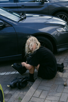 Teenager with blonde hair putting on inline skates