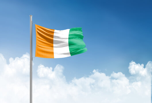 Ivory Coast flag waving in beautiful sky.