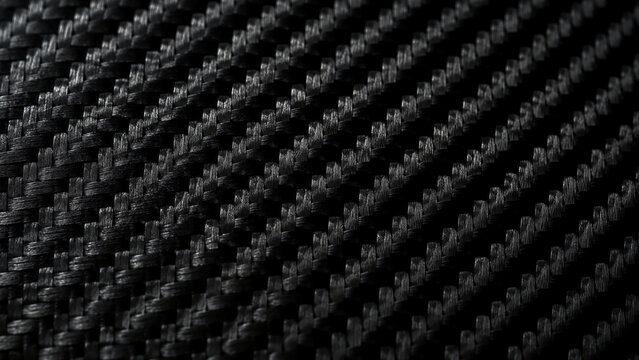 Close-up image of black carbon fiber fabric with a woven texture and reflective surfaces creating a sleek, high-tech appearance.