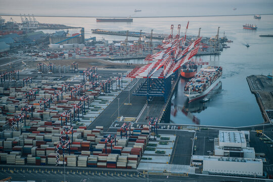 A container ship docked at a busy port with cranes and cargo