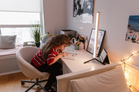 Teenage girl reading book during a casual gathering with friends indoors