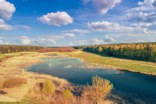 Aerial view of countryside and winding brook in the evening at sunset light. Beautiful nature landscape with cloudy sky