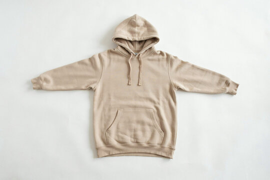 Beige hoodie laid flat on white background, casual streetwear sweatshirt with hood and drawstrings, minimalist apparel mockup for online shop