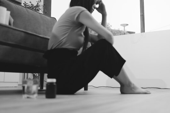 Young Asian woman sitting in bed and holding her head in pain with headache, feeling depressed 

and suffering