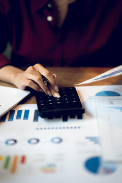 Business professional calculating financial data while reviewing charts and reports, representing accounting, budgeting, investment analysis and financial planning.