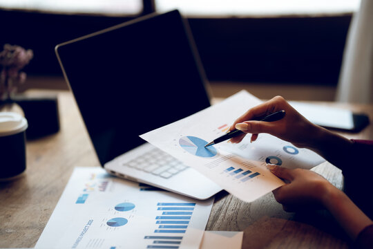 Business professional reviewing financial reports and analyzing charts at a desk, representing accounting, financial planning, data analysis and business management.