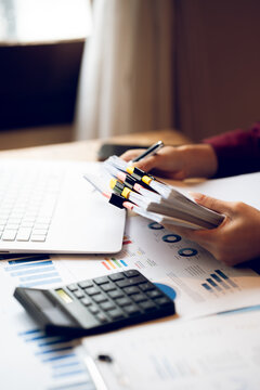 Business professional working on a laptop with financial charts, calculator, documents and coffee on a wooden desk, representing finance, accounting and office work.