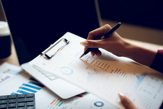 Business professional reviewing financial reports and analyzing charts at a desk, representing accounting, financial planning, data analysis and business management.