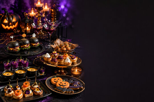 Halloween party table with spooky food drinks pumpkins and candles