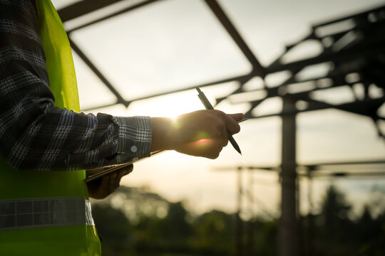 inspector or engineer is inspecting construction and quality assurance new house using a checklist. Engineers or architects or contactor work to build the house before handing it over to the homeowner
