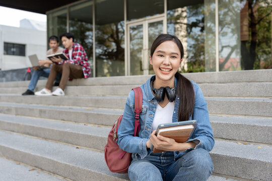 Beautiful student asian woman with backpack and books outdoor. Smile girl happy carrying a lot of book in college campus. Portrait female on international Asia University. Education, study, school
