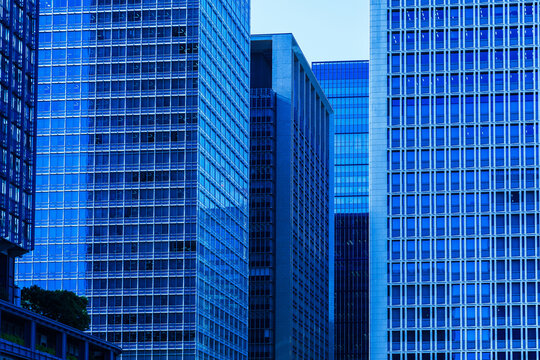 Modern high-rise office towers with geometric glass facade and blue grid pattern in Tokyo business district.