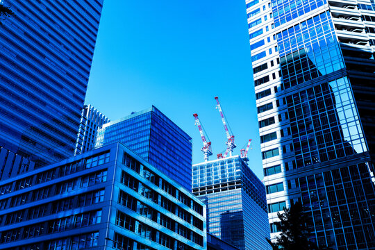 Modern skyscrapers and construction tower cranes building new office architecture in Tokyo business district under blue sky.