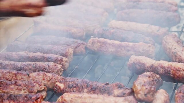 Grilling sausages on barbecue with smoke rising, close-up of cooking process