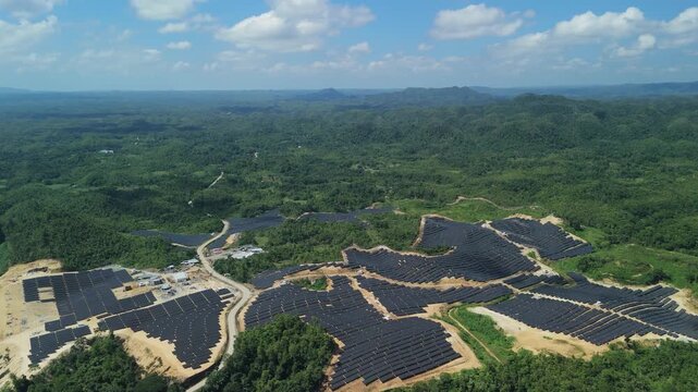 High-altitude drone ascends and pulls back over hillside solar arrays, access roads, and the rural landscape surrounding Sikatuna, Bohol