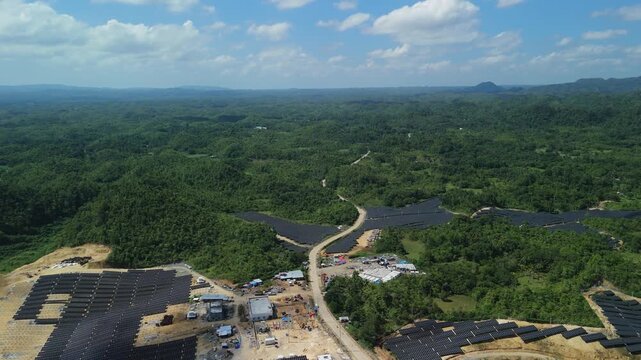 Drone pulls back over hillside solar arrays and access roads, revealing the Sikatuna Solar Power Plant and rural Bohol landscape