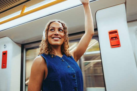 Commuting woman stands on train with headphones during journey
