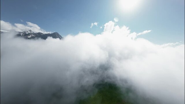 Aerial view of clouds rolling over green mountains under bright sunlight