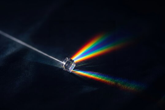 Ein Prisma mit Regenbogenfarben vor schwarzem Hintergrund