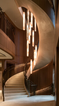 Vertical view of elegant luxury spiral staircase in modern interior with hanging vertical tube pendant lights.
